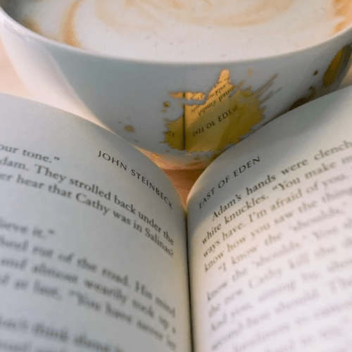 A cup of coffee with gold speckles in front of an opened book